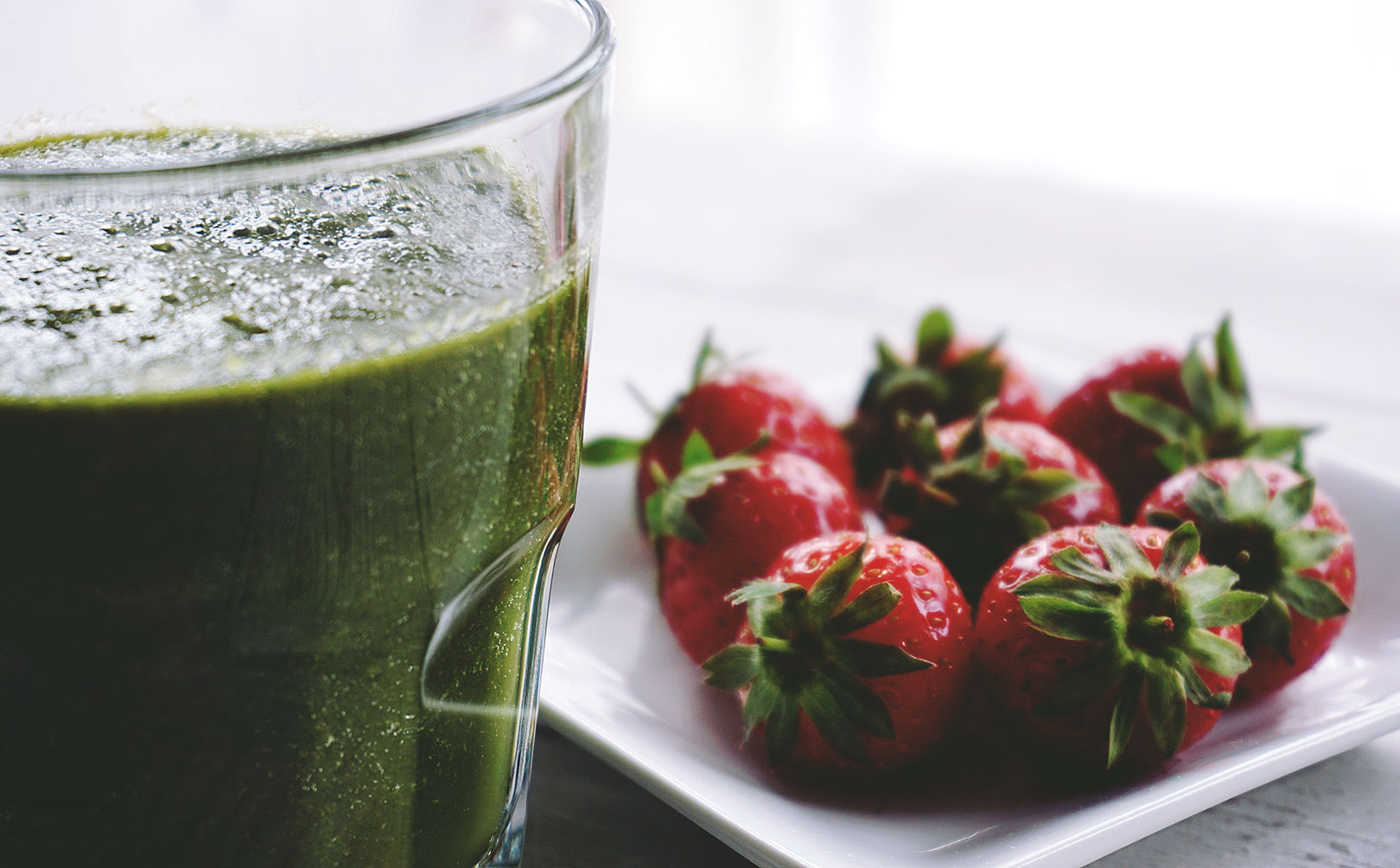 Un verre de smoothie au kiwi accompagné d'une assiettes de fraises fraiches